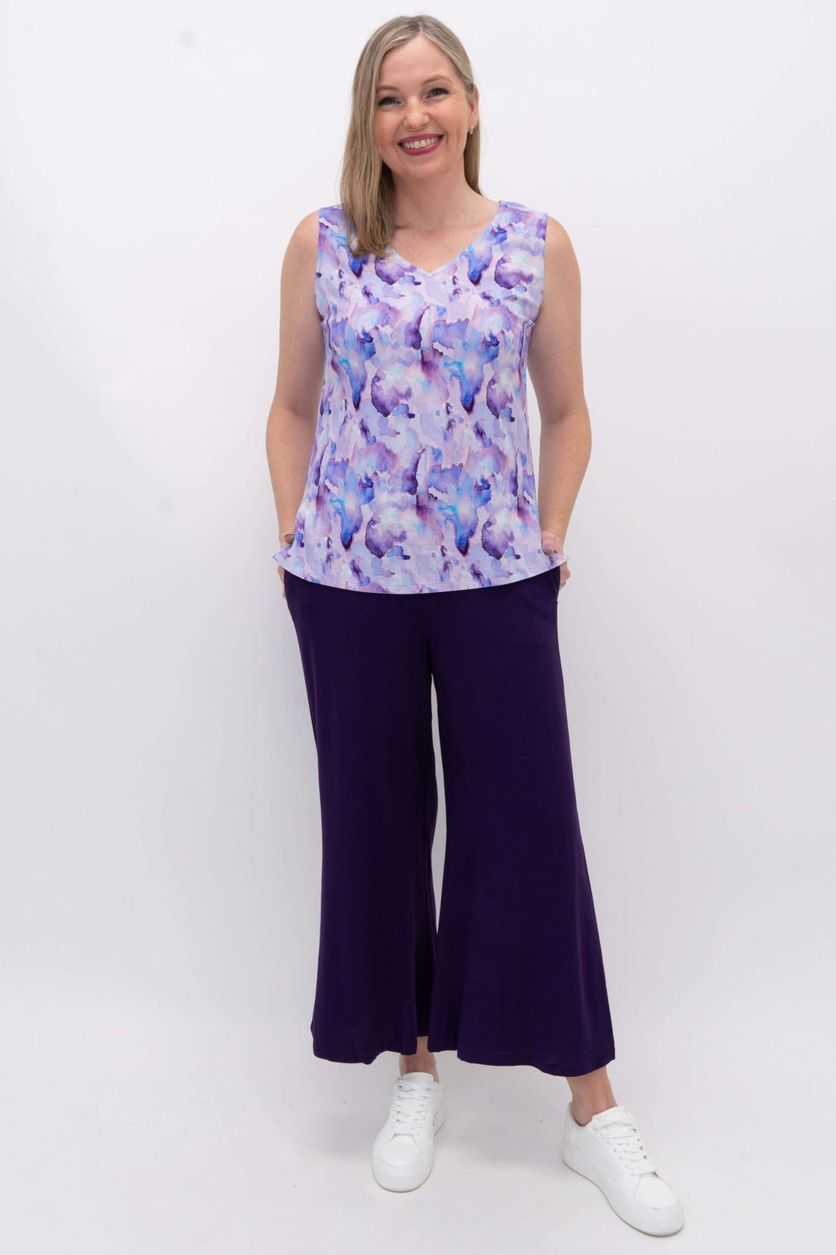 Model wearing a purple watercolor tank top with wide leg purple pants and sneakers
