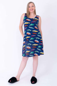 Woman playfully posing in blue dress with retro car print and black slippers