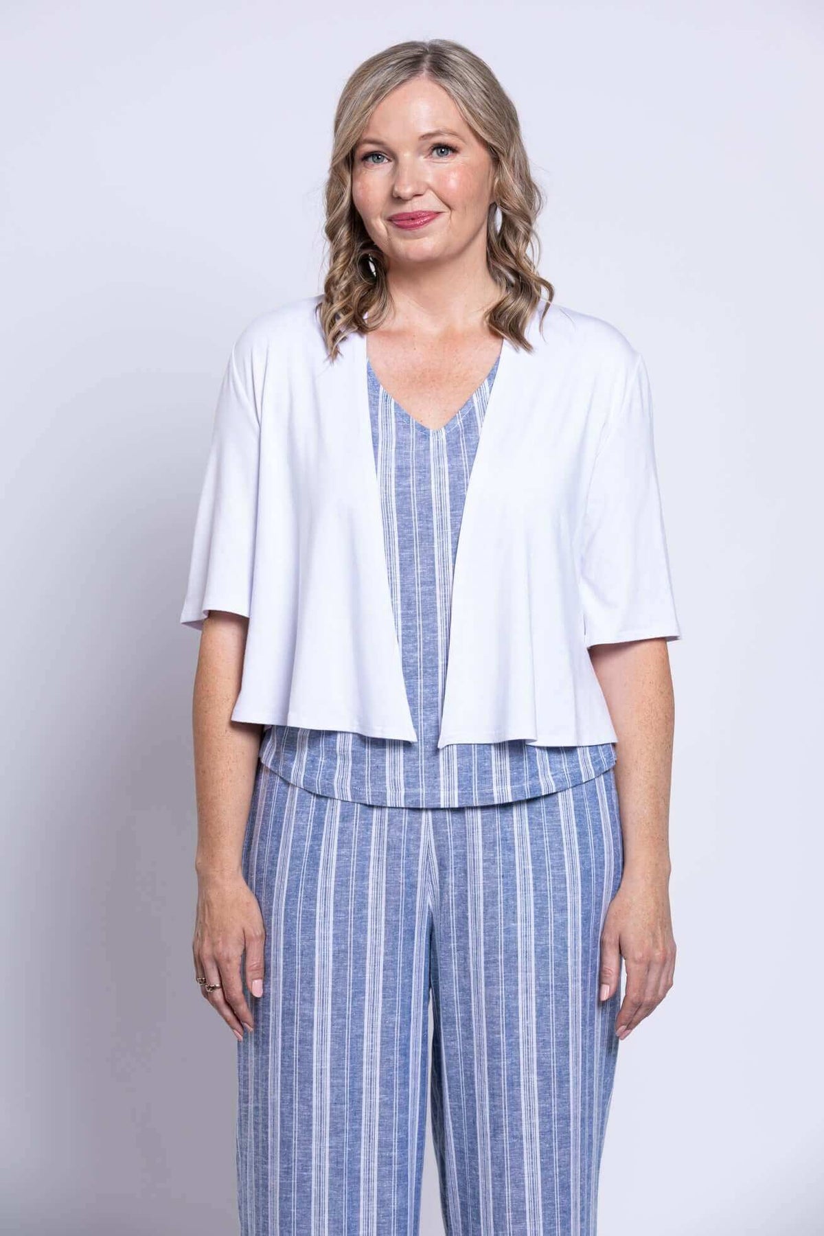 Model with white cardigan over blue stripe Landon Capri Pants and top, front view