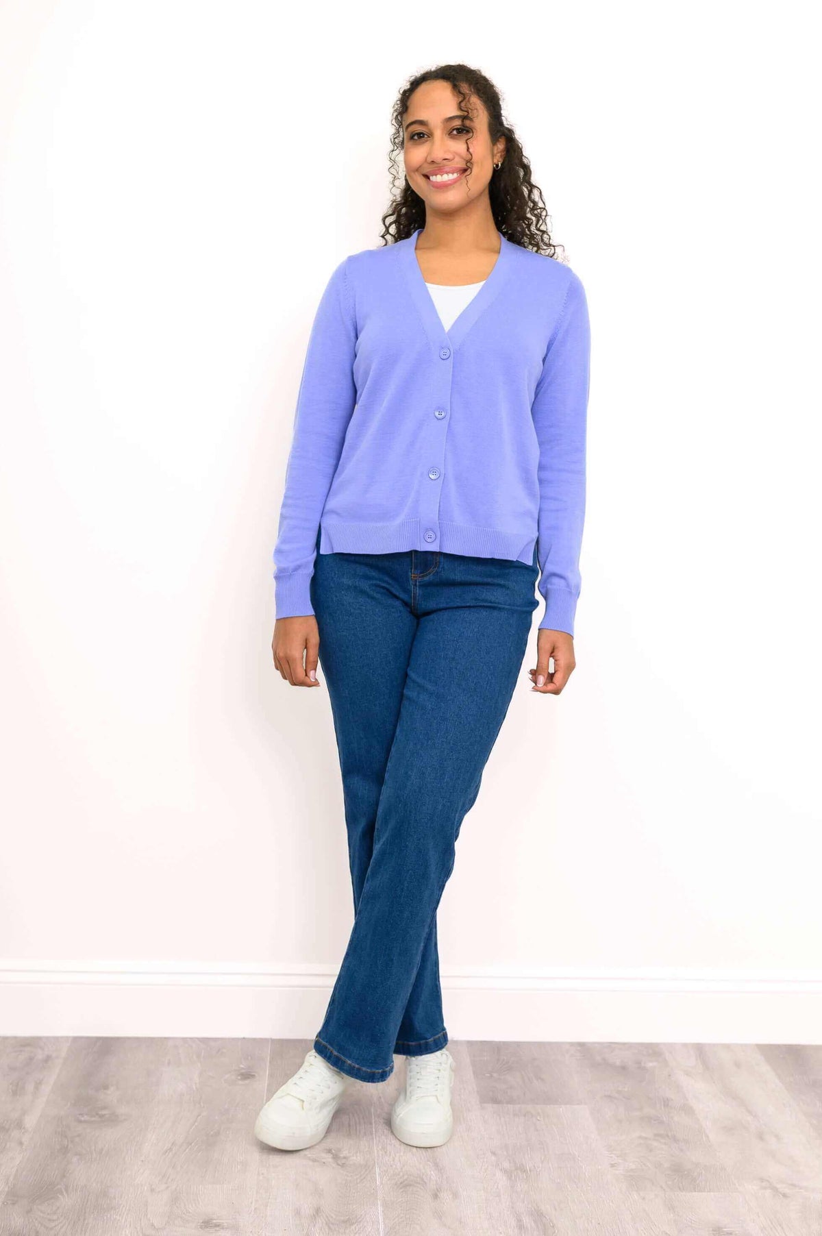Model standing in light purple cardigan and blue jeans with one leg crossed