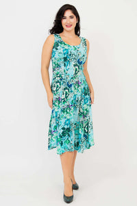 Model posing with hands in pockets in an aqua floral A-line dress