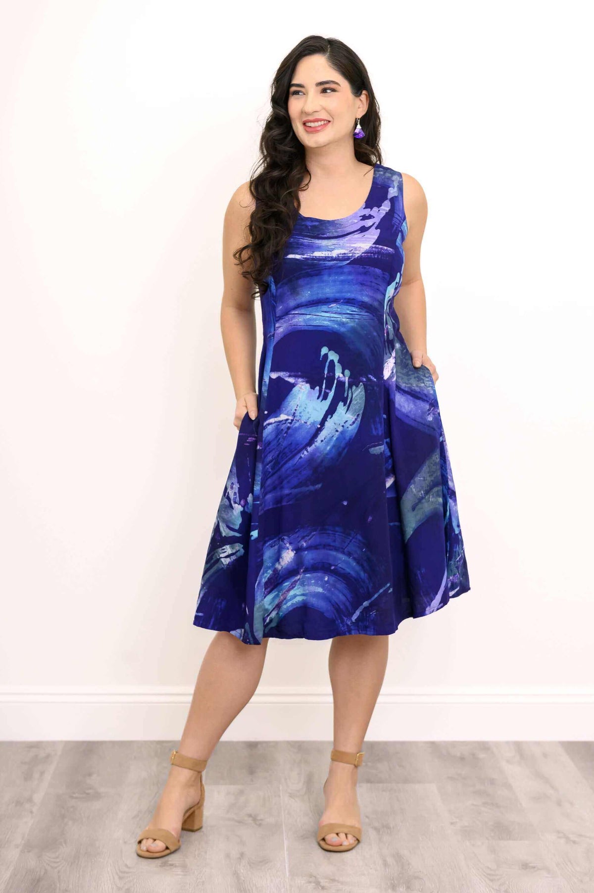 Model showing side pockets on abstract blue swirl sleeveless dress