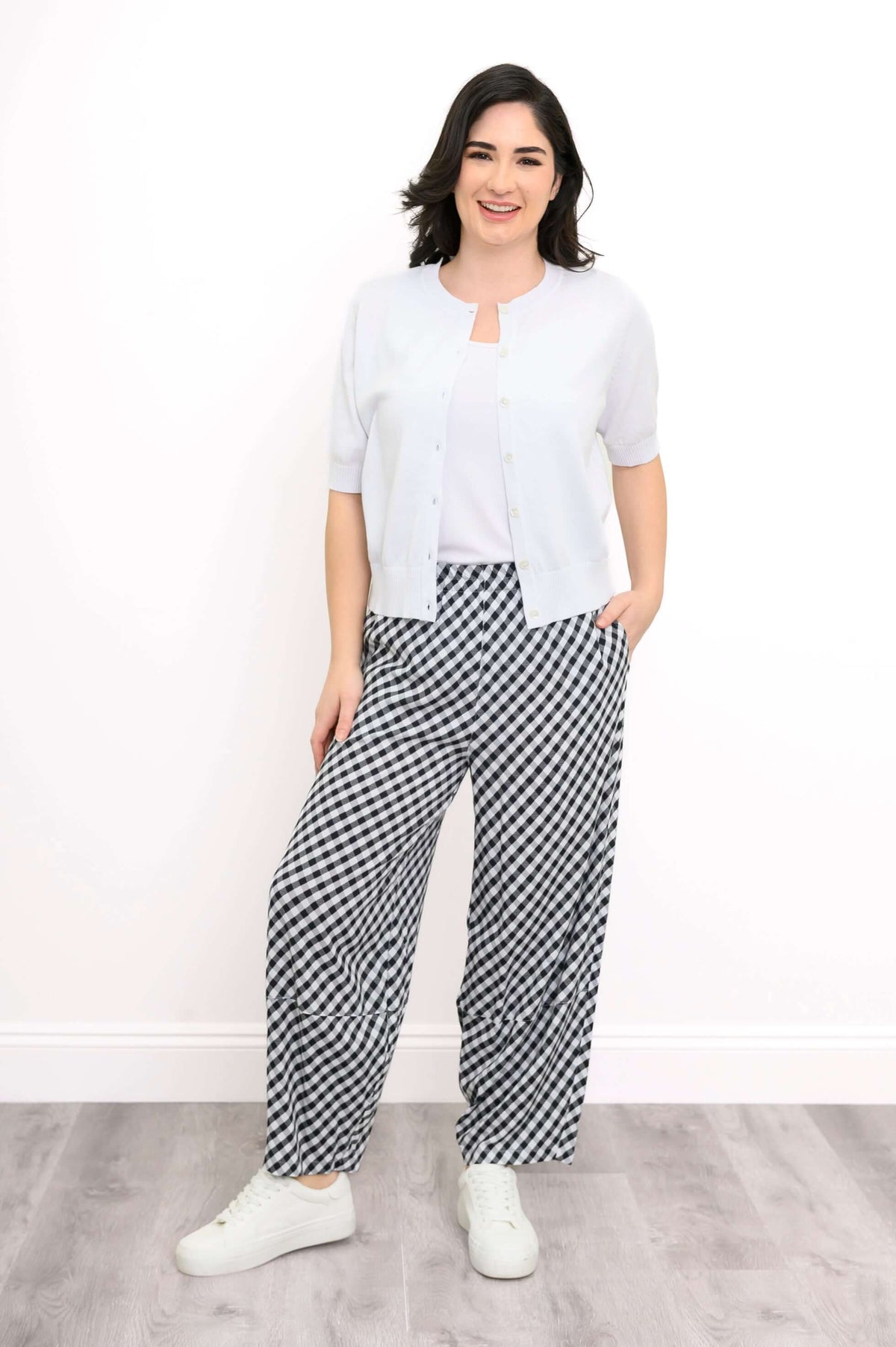 Model styled in short-sleeve white cardigan and black gingham wide-leg pants