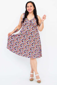Smiling woman holding out the skirt of a floral fit and flare dress