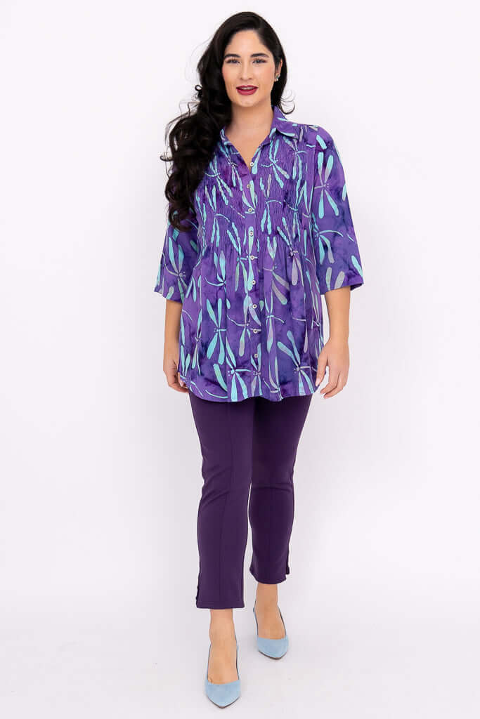 Model walking forward wearing Cindy violet dragonfly smocked blouse and purple pants