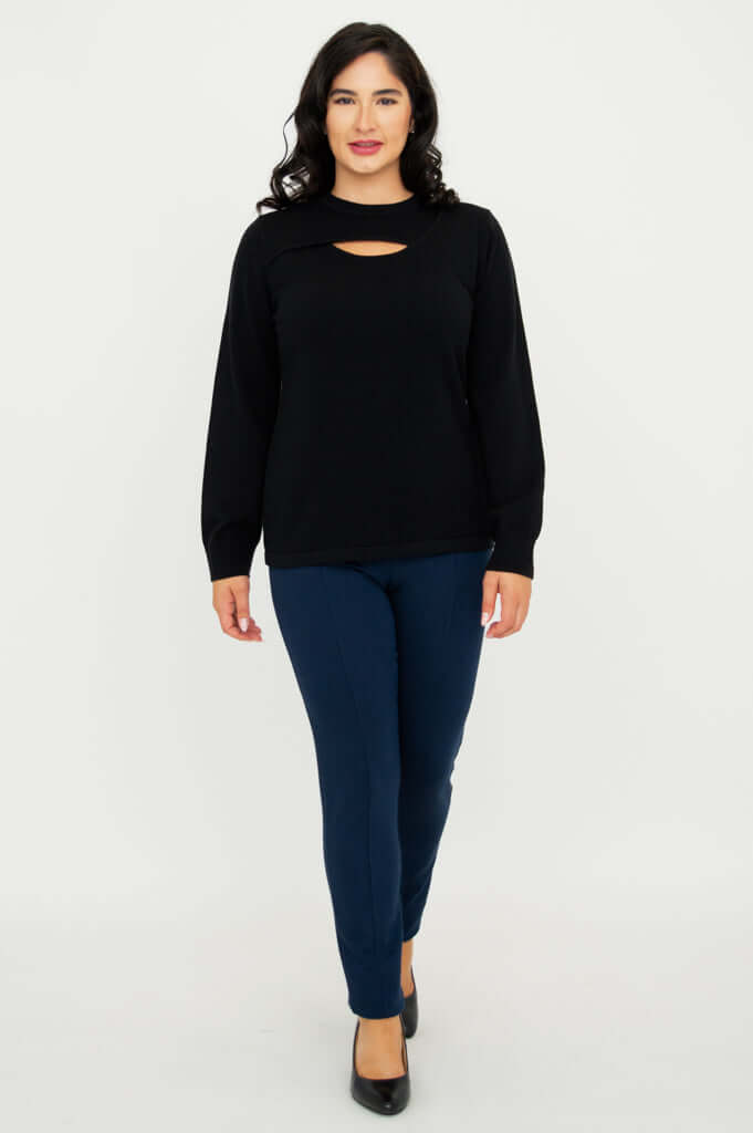 Model walking forward in black sweater with neck cutout and blue pants