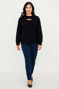 Model walking forward in black sweater with neck cutout and blue pants