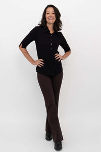 Model smiling and wearing Daya Flared Modal Pants in coffee with a black button-down top