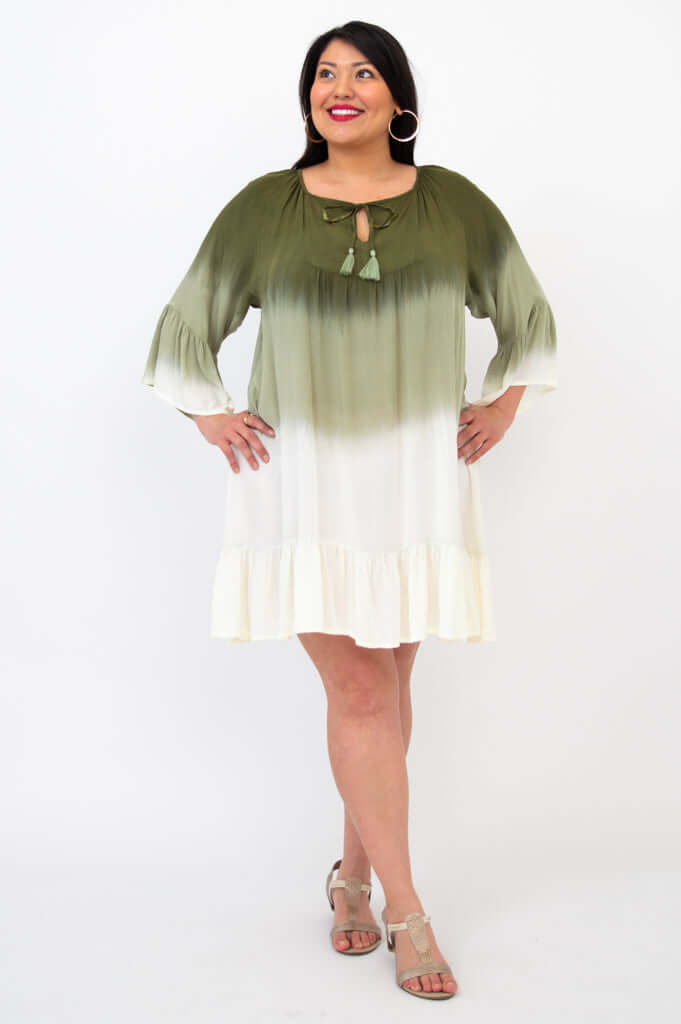 Smiling woman modeling a gradient green and white dress with 3/4 sleeves and tassel neckline