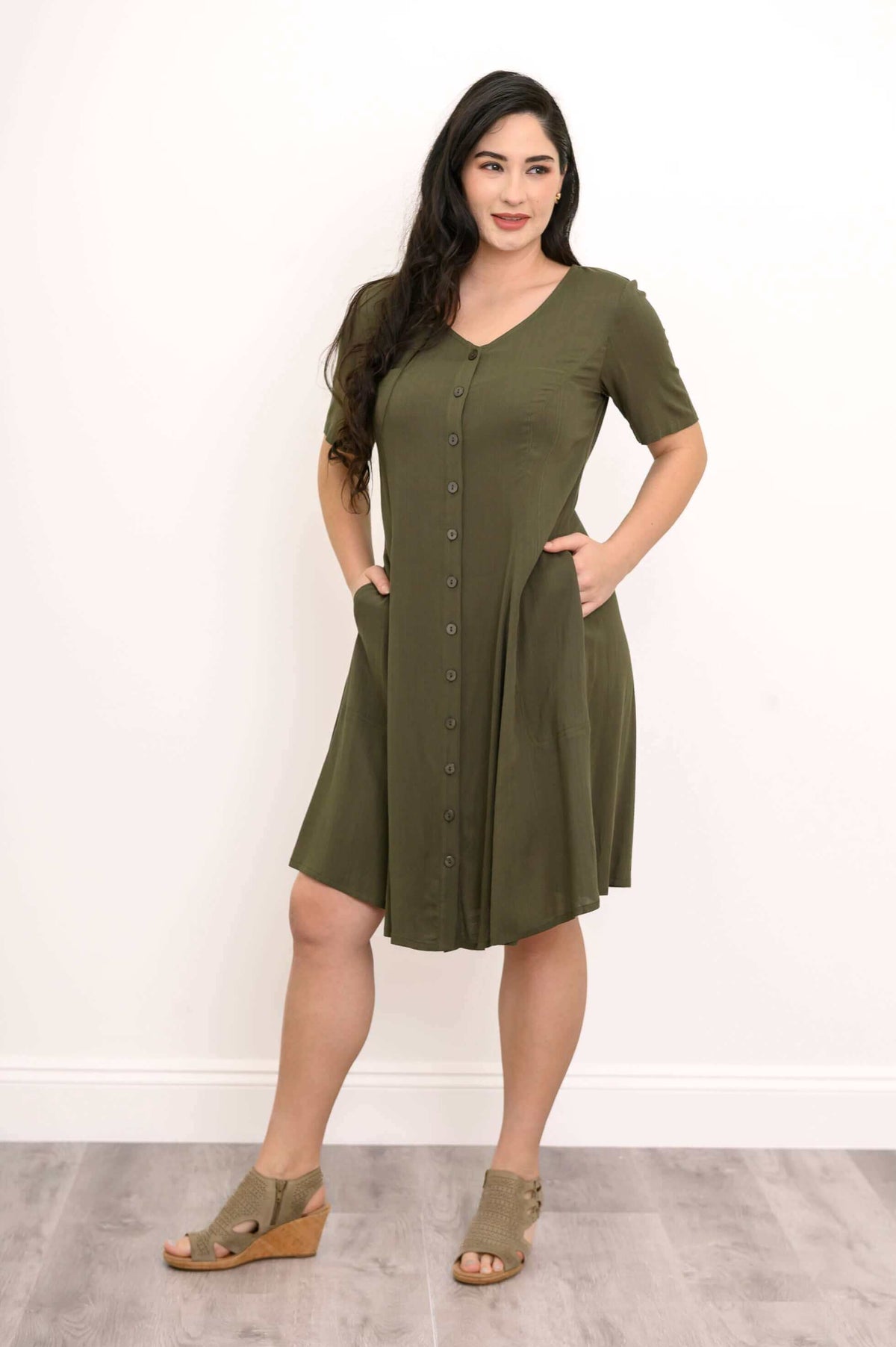 Woman posing with hands in pockets wearing olive green princess seam dress