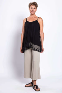 Woman modeling a black tank top with lace hem paired with beige wide-leg pants