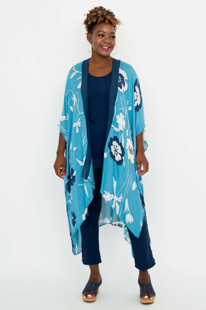 Woman smiling in a blue floral kimono wrap, facing forward with hands by her sides