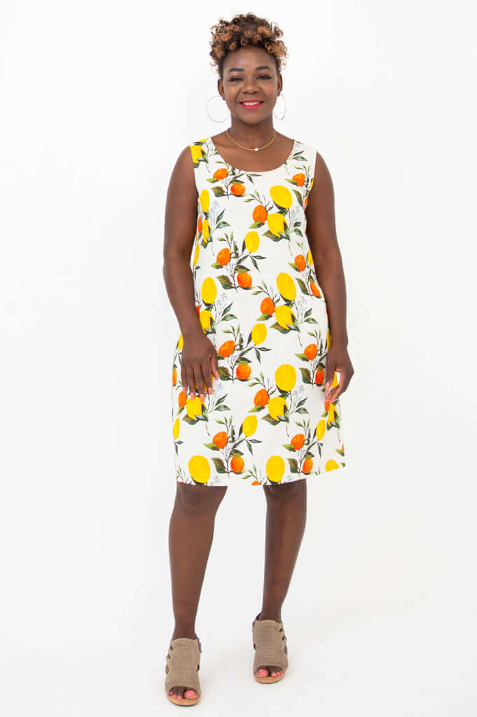 Woman standing in sleeveless shift dress with bold citrus fruit pattern