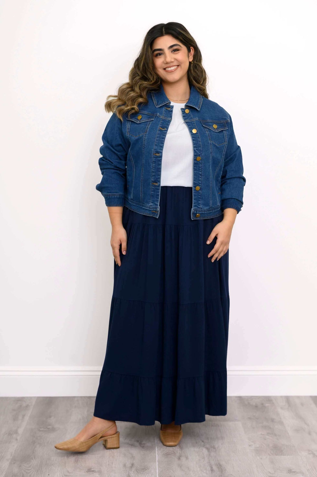 Model wearing denim jacket and navy Roma tiered maxi skirt, standing and smiling