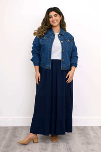 Model wearing denim jacket and navy Roma tiered maxi skirt, standing and smiling