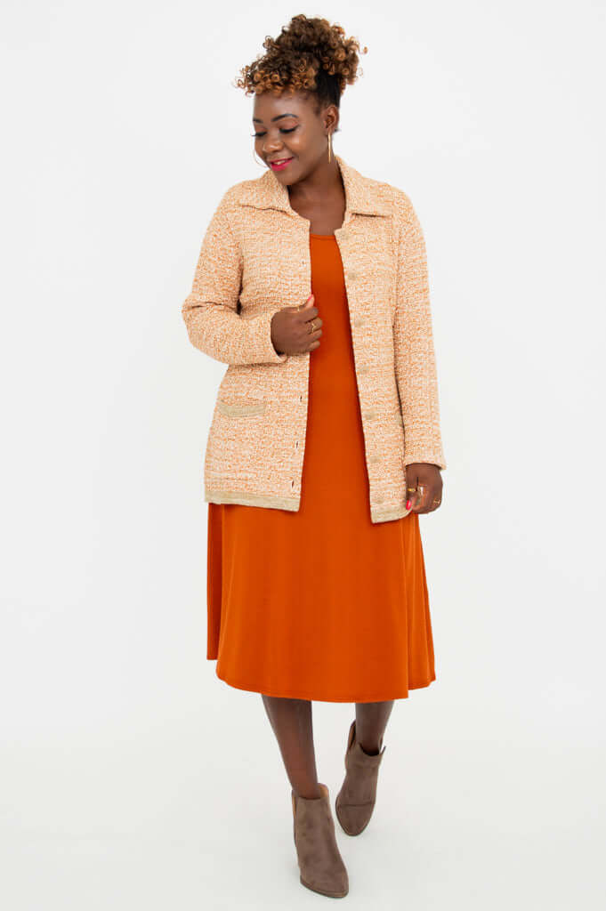 Model in tan Chanel Cardigan with front open, showing matching orange dress and taupe boots