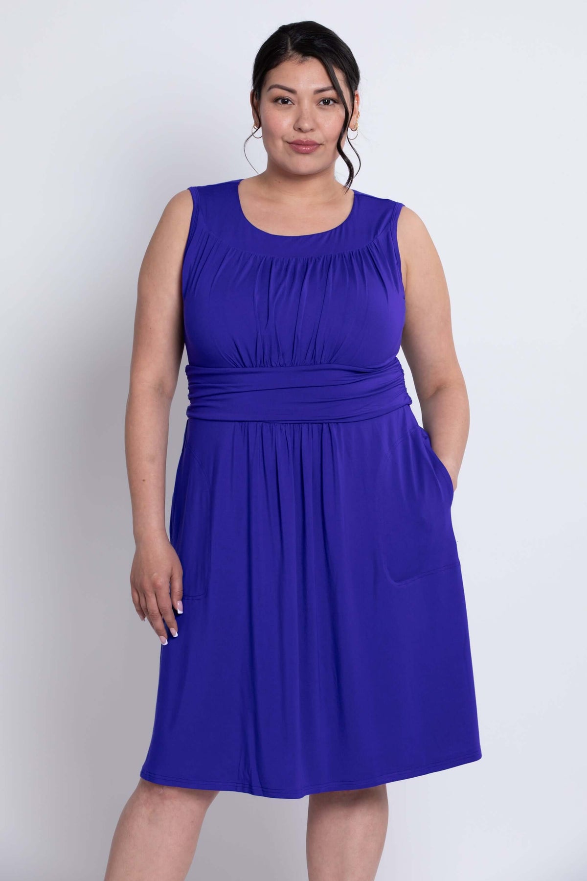 Model with hands in pockets, wearing sleeveless purple bamboo dress, front view