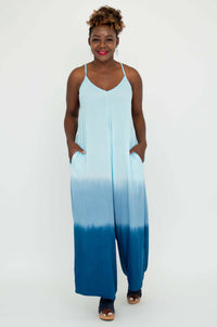 Model standing with hands in pockets, showcasing a blue tie-dye jumpsuit