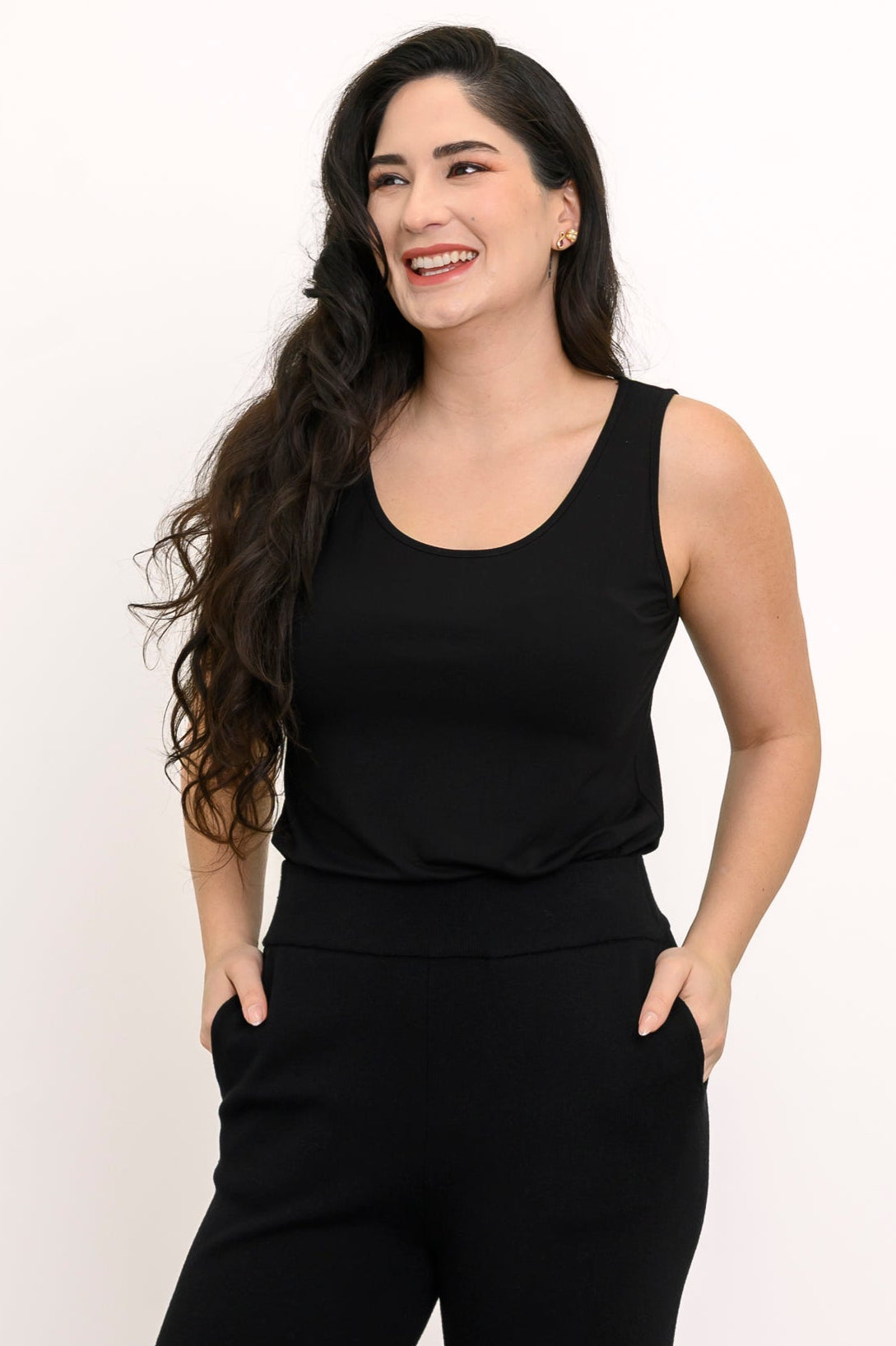 Close-up view of a woman wearing a black sleeveless bamboo scoop neck tank top against a white background.