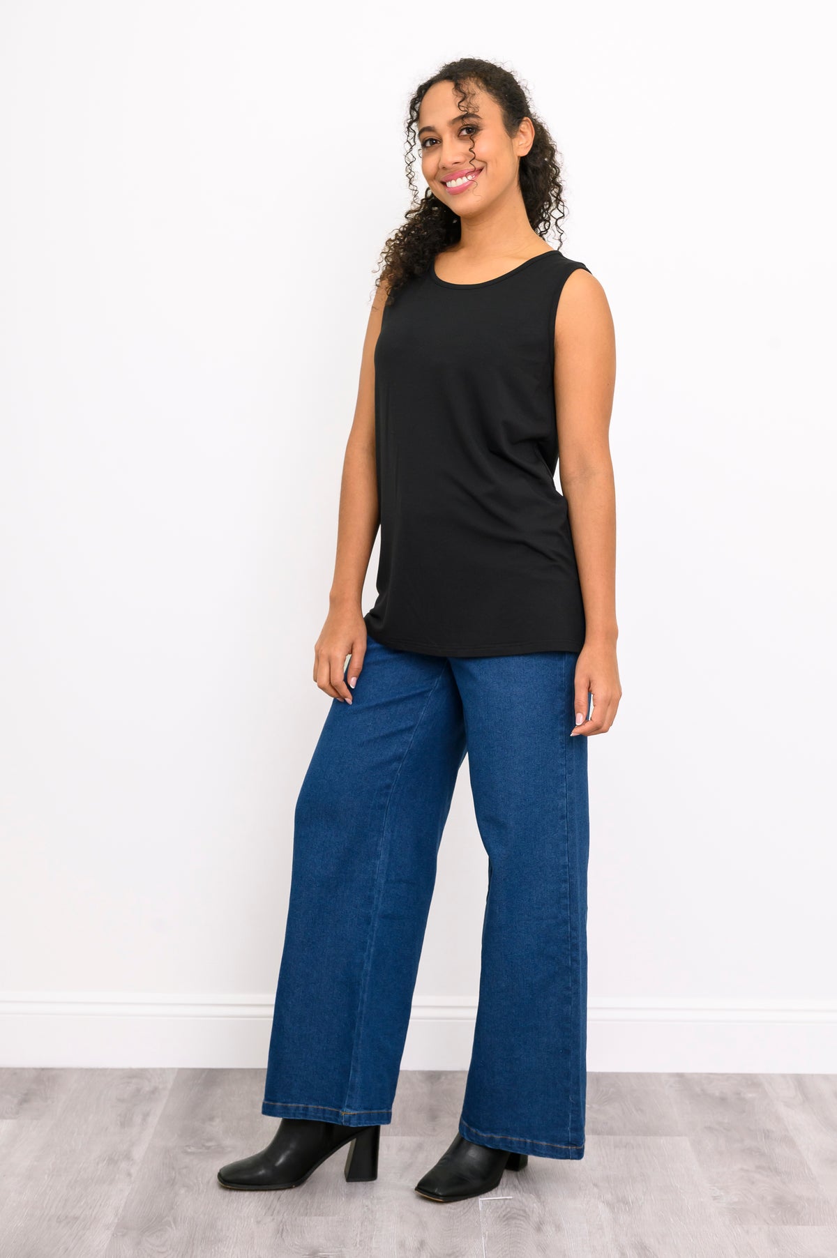 Angled front view of a women's structured black sleeveless top with a scoop neckline and long length.