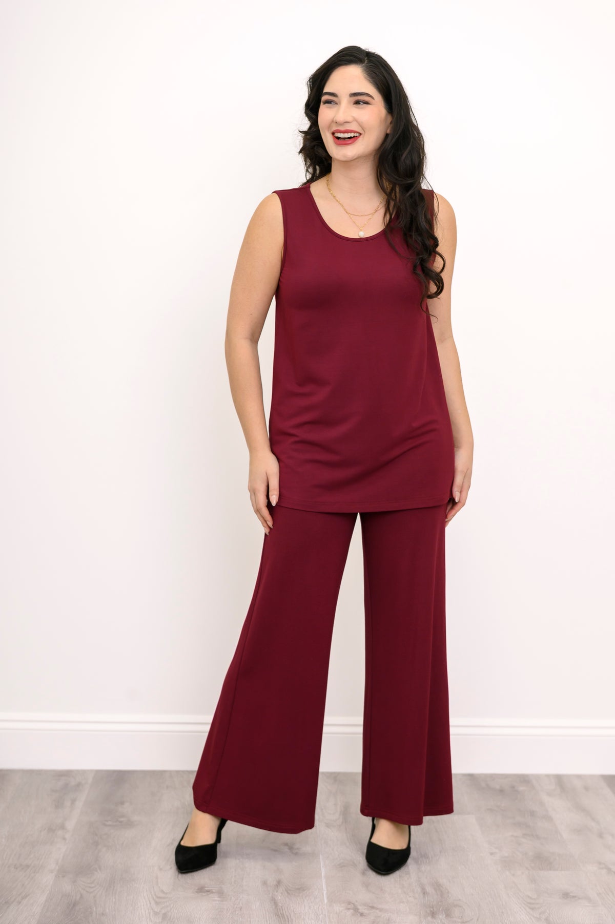 Wide studio shot of a relaxed-fit burgundy bamboo French terry sleeveless top styled with monochrome trousers.