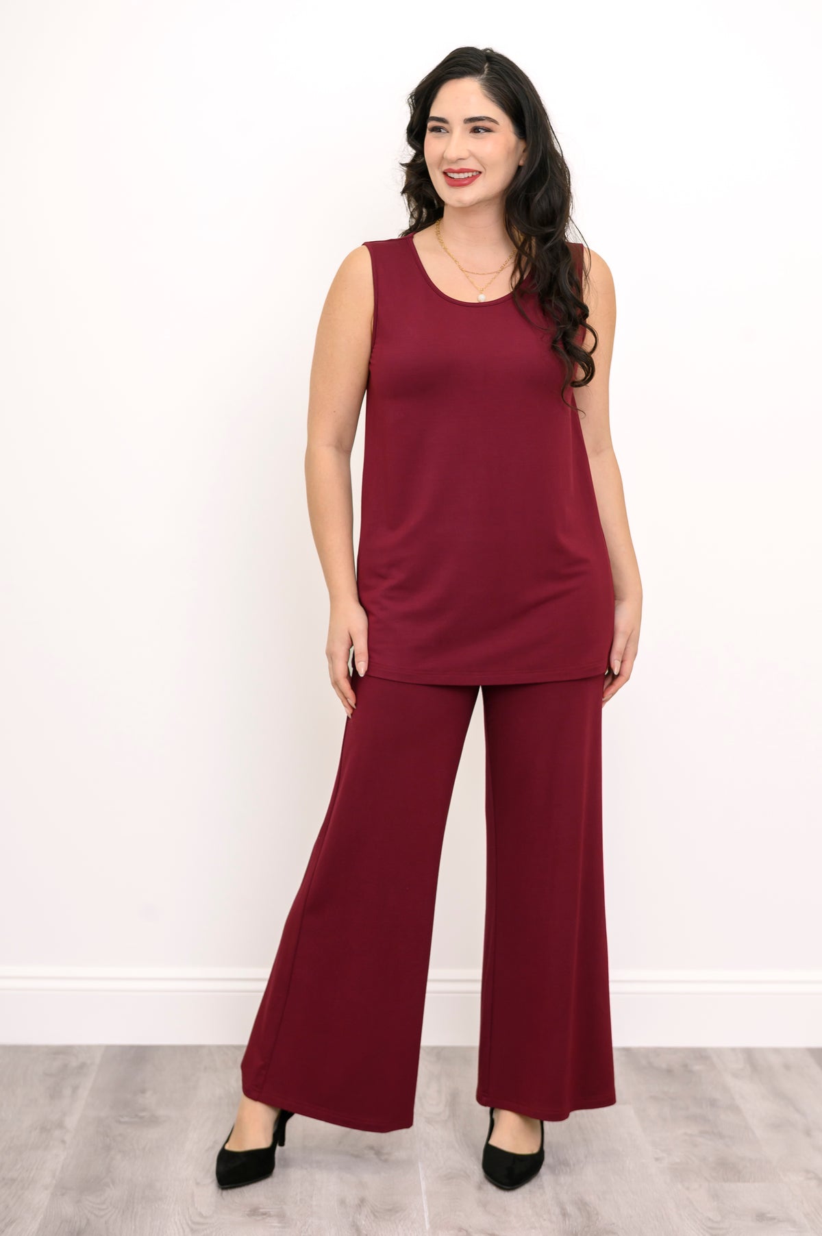 Full-length front view of a woman styling a burgundy sleeveless tank top with matching wide-leg trousers.