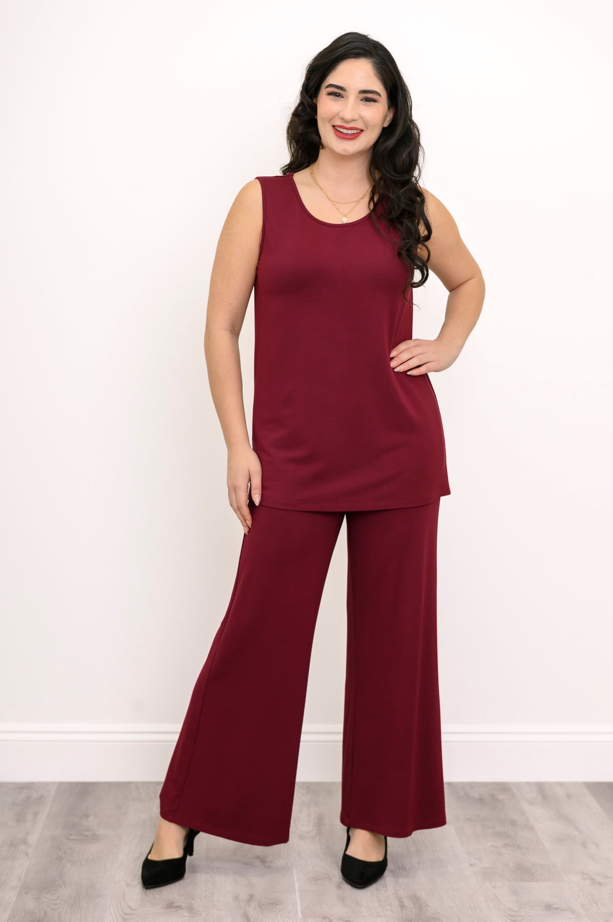 Full-length front view of a woman wearing a burgundy sleeveless knit tank top paired with matching wide-leg pants.