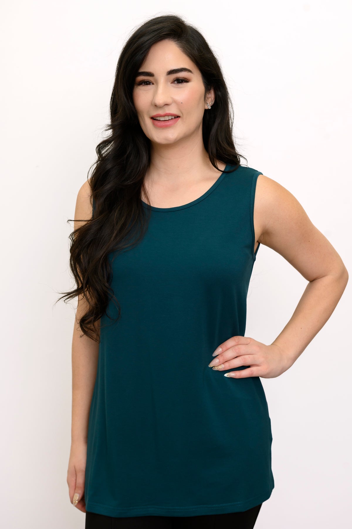 Front view of a smiling woman wearing a scoop neck crystal teal bamboo French terry tank top with black pants.