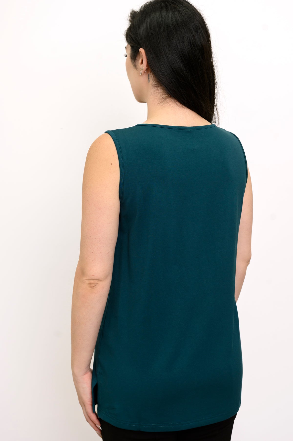 Rear studio shot of a loose-fit teal sleeveless top with a clean straight hemline, styled over black trousers.