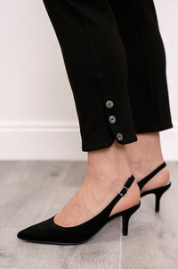 Close up view of bottom hem of woman's pants showing button detail and rounded edge