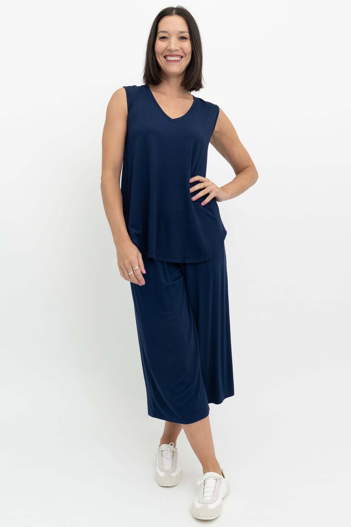 Woman modeling navy blue V-neck top and culotte pants with one hand on hip
