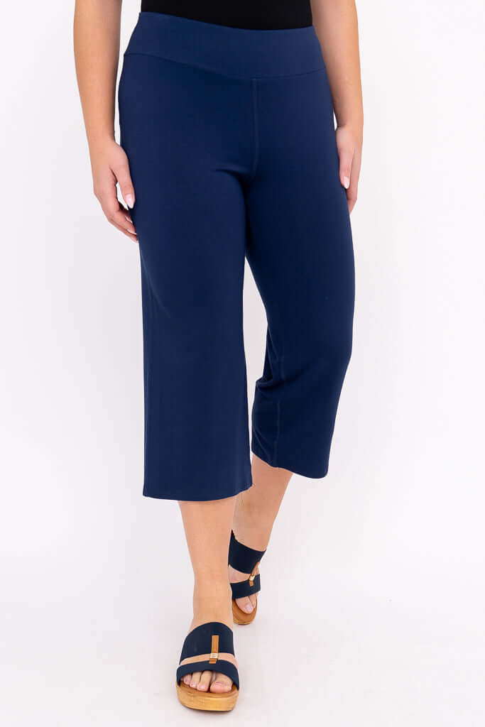 Walking pose in navy blue yoga capri pants, cropped length