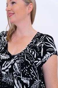 Close-up of neckline and sleeve details on black and white leafy dress