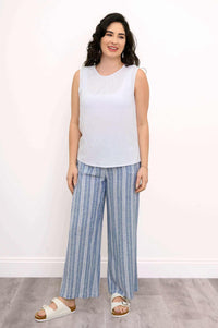 Woman modeling the Nina tank in white, full outfit with striped pants and sandals