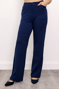 Woman wearing navy blue pants with pockets and navy blue shoes on a white background, front view