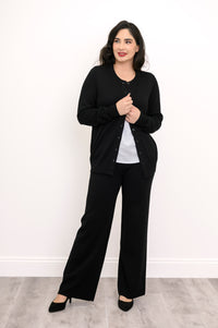 Front view of a woman wearing a black crewneck button up cardigan styled over a white t-shirt.