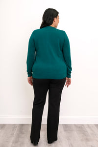 Back view of a woman wearing a hip length emerald green cotton viscose knit cardigan in studio.