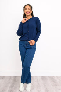Front view of a woman wearing a navy crewneck button up cardigan styled with blue denim jeans.