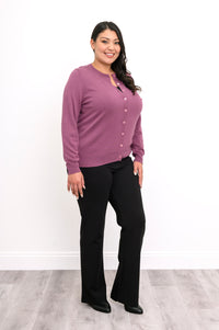 Full length view of a woman wearing a vintage pink cotton viscose cardigan sweater and black pants.