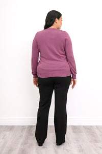 Back view of a woman wearing a hip length vintage pink cotton viscose knit cardigan in studio backdrop.