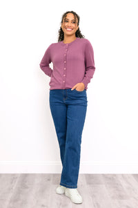Front view of a woman wearing a pink crewneck button up cardigan styled with dark wash denim pants.