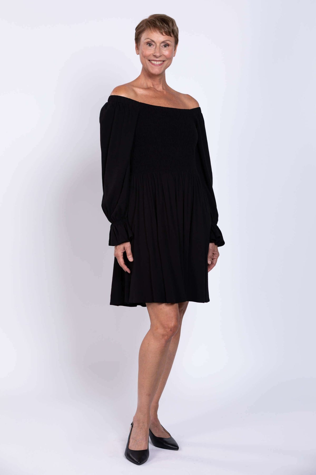Black dress styled off-shoulder with long ruffled sleeves on model