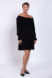 Black dress styled off-shoulder with long ruffled sleeves on model