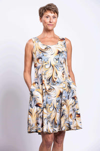 Older woman in sleeveless swirl print dress standing with hands in pockets