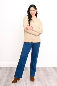 Cream mock neck pullover shirt with structured sleeves and a rolled hem finish, styled with blue denim.