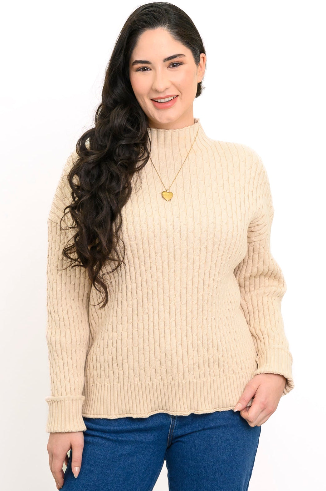 Smiling woman wearing a beige funnel neck knit sweater and a gold chain necklace, shown in a front-facing view.