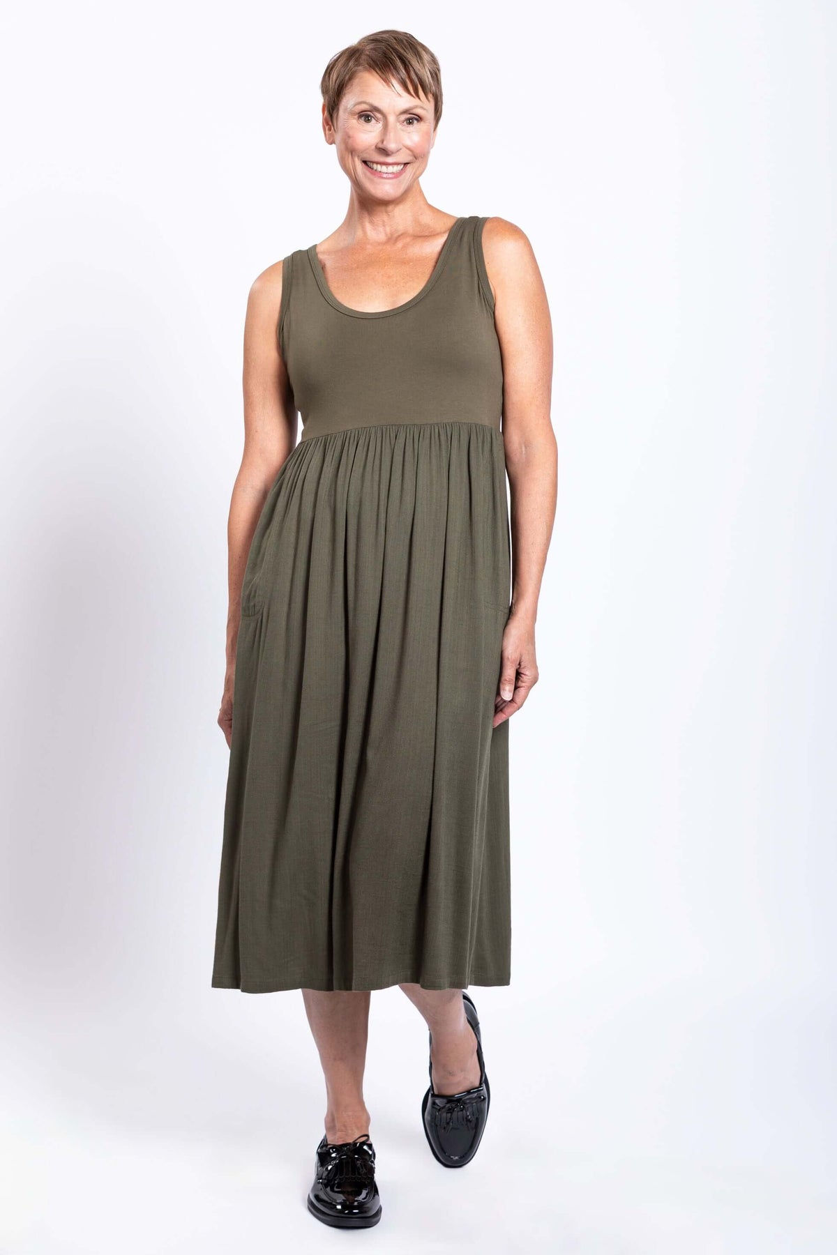 Smiling woman posing in olive green empire waist midi dress