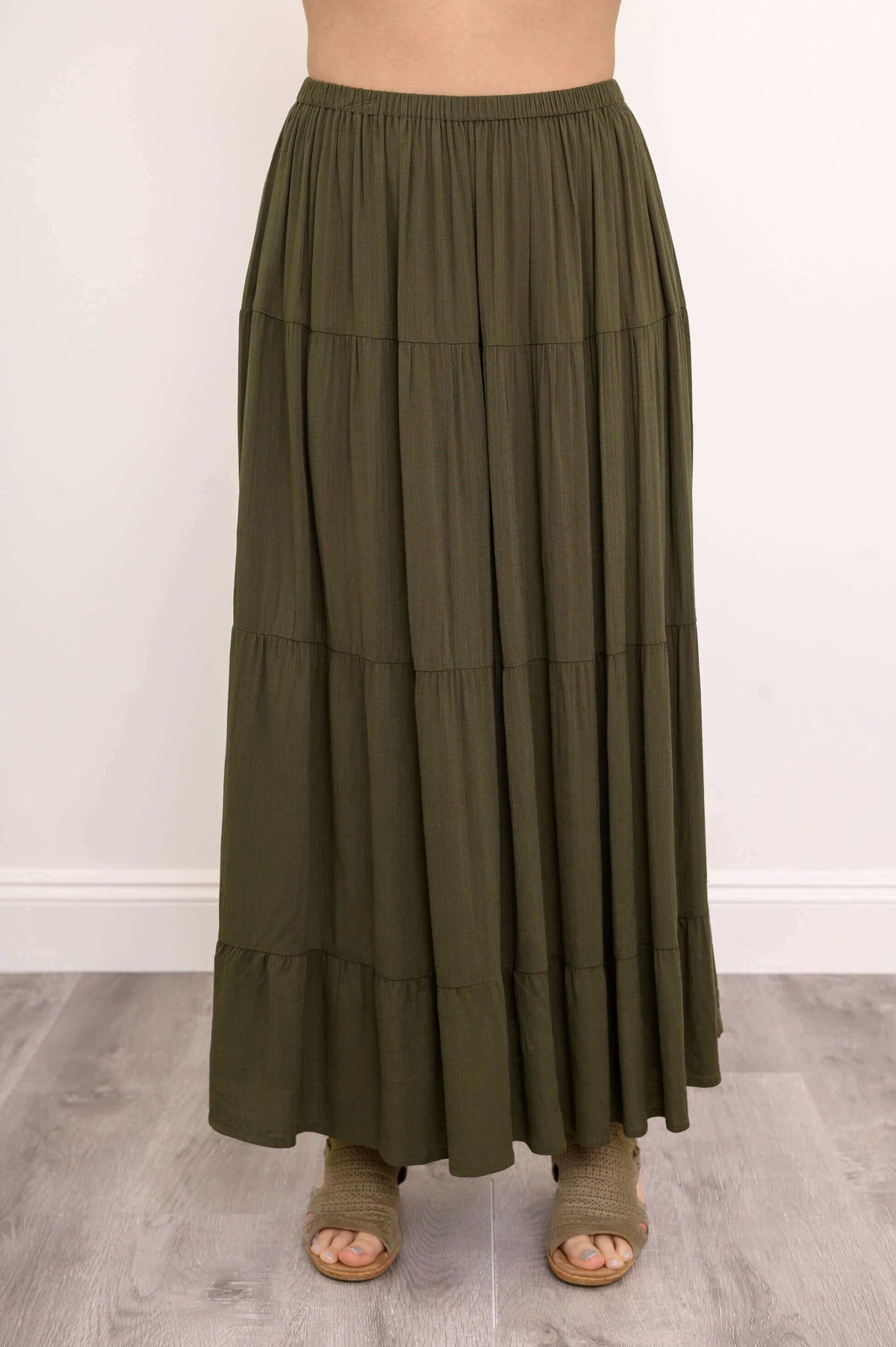 Close-up of olive green tiered maxi skirt with elastic waistband and flowing fabric