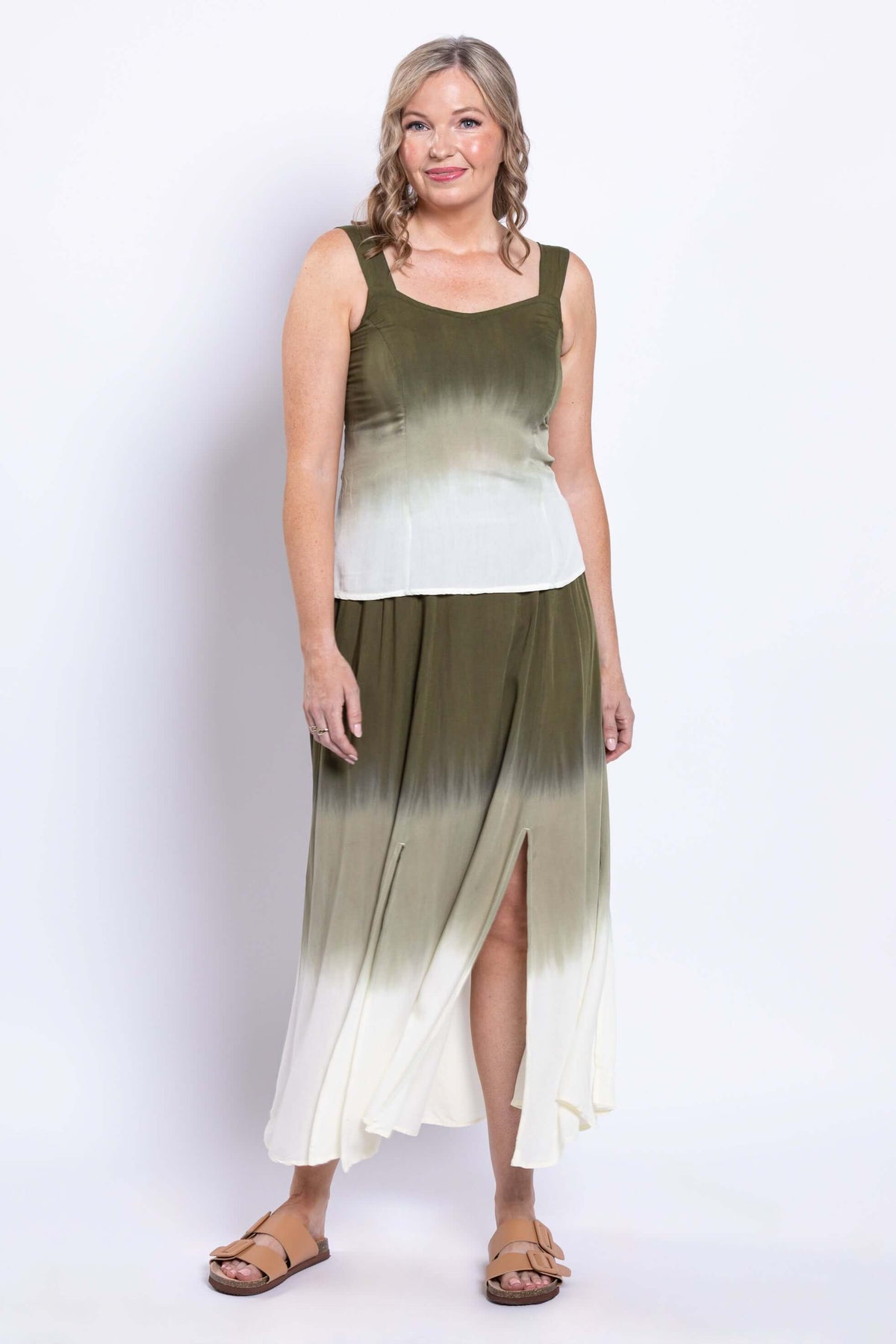 Woman in olive ombre sleeveless tank and skirt with side slit, standing and smiling