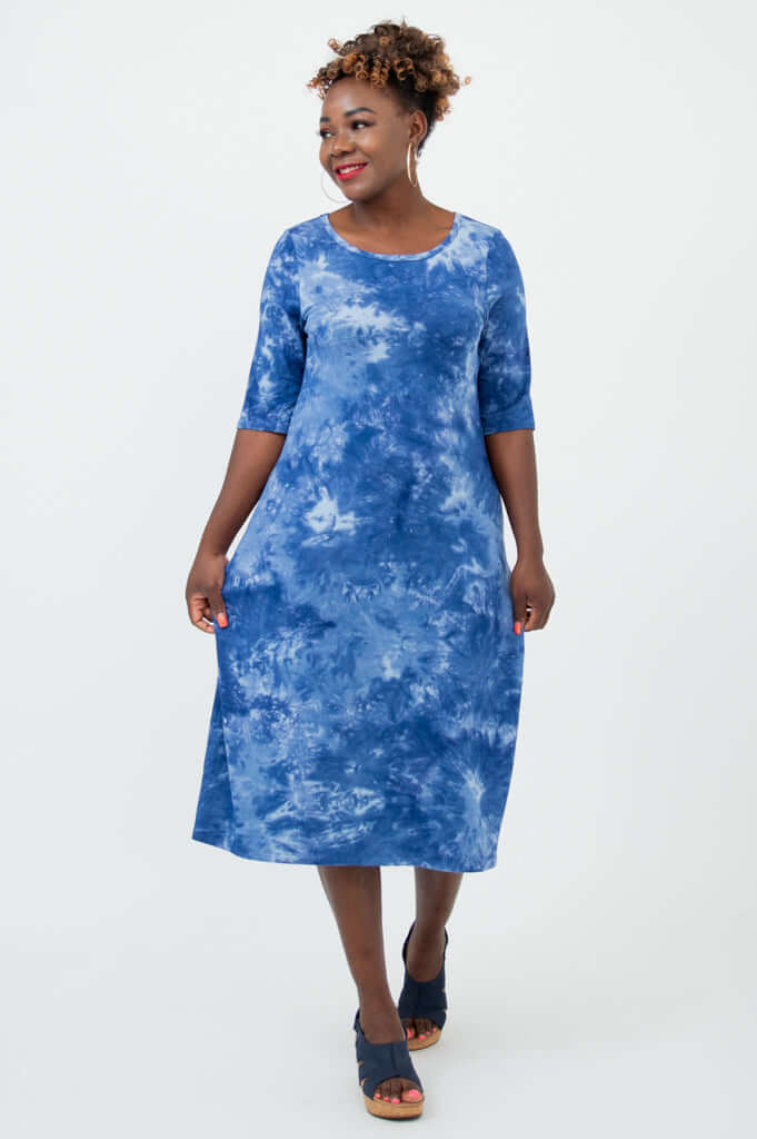 Woman modeling a blue bamboo tie dye dress with elbow length sleeves, walking pose